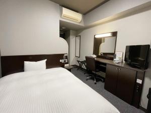 a hotel room with a bed and a desk and a mirror at Hotel Route-Inn Ina Inter in Minamiminowa
