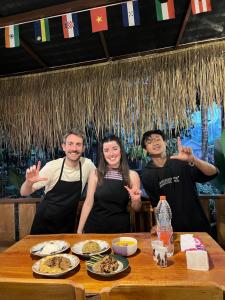 a group of three people standing at a table with food at Aulia Bungalows Tetebatu in Tetebatu