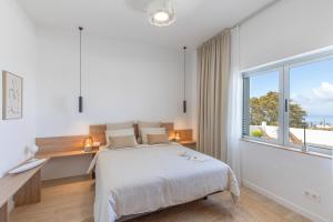 a white bedroom with a bed and a large window at Glück House In Las Norias in Las Manchas