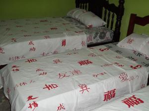 two beds with asian writing on a white bedspread at Pousada Del Rio (Santa Rita De Cassia) in Carolina