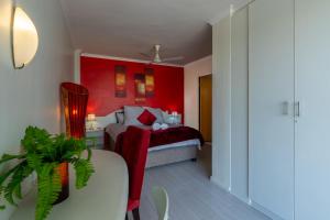 a bedroom with a bed with a red wall at 419 Ocean Breeze in Cape Town +14 photos