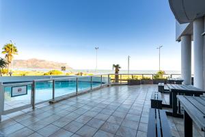 a balcony with benches and a view of the beach at 419 Ocean Breeze in Cape Town