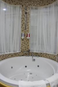 a white bath tub in a bathroom with a window at Batumi World Palace in Batumi +63 photos