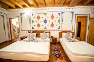 two beds in a room with a wall with a picture at As-Salam Boutique Hotel in Bukhara
