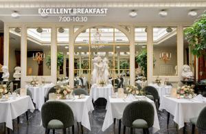 a restaurant with white tables and chairs and a statue at Grand Palace Hotel - Small Luxury Hotels of the World in Riga