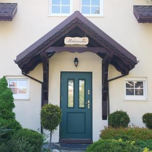 a green door on a white house at Molonówka Guest House in Szczyrk