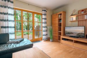 a living room with a couch and a flat screen tv at Höfthus 8 - Bade- & Saunawelt täglich inklusive in Alt Reddevitz
