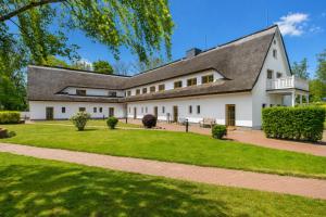 a large white building with a gray roof at Höfthus 8 - Bade- & Saunawelt täglich inklusive in Alt Reddevitz