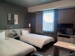 a hotel room with two beds and a television at Hotel Route-Inn Nihonmatsu -Kokudo 4Gou- in Nihommatsu