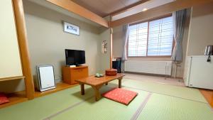 a living room with a table and a tv and a table sidx sidx at 昆布川温泉幽泉閣 in Rankoshi