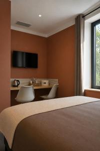 a bedroom with a bed and a desk and a television at Côté Nuit in Capestang
