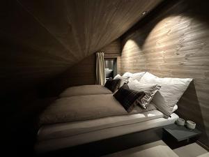 a bed in a room with a wooden wall at Hafjell Luxury Lodge in Øyer