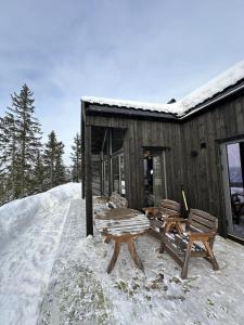 a wooden cabin with two benches in the snow at Hafjell Luxury Lodge in Øyer