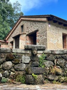 a stone building behind a stone wall at Apartamentos El Escondite de Pedro Malillo in Candeleda
