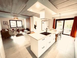a kitchen with white cabinets and a living room at La maison d'à côté - Sart in Jalhay