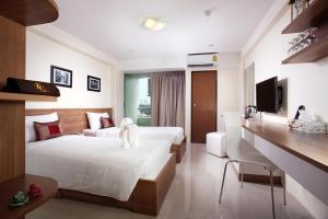 a hotel room with two beds and a desk at KC PLACE Hotel Srinakarin in Bangna
