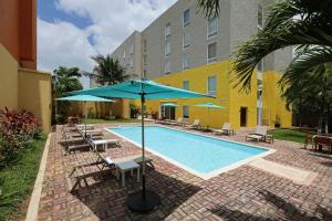 a pool with chairs and umbrellas next to a building at City Express by Marriott Cancun in Cancún