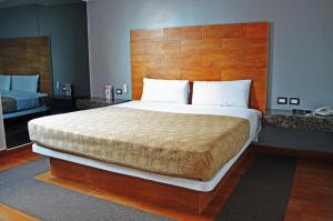 a bedroom with a large bed with a wooden headboard at Hotel Santa Cruz in Mexico City