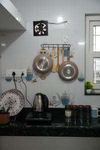 a kitchen counter with utensils and pans on the wall at Retreat Homes in Siliguri