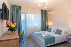 a hotel room with a bed and a vase of flowers at Casa Asteria - Mamaia Nord in Mamaia Sat/Năvodari
