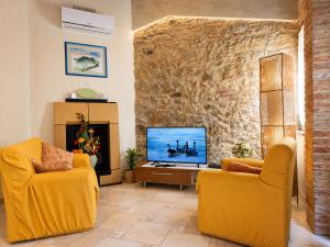 a living room with two yellow chairs and a television at Sant'Ippolito in Asciano