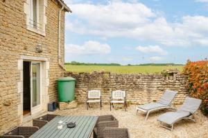 a patio with chairs and a table and a stone wall at Ambre à la Rochelle in Vergné