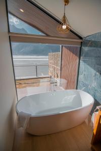 a bath tub in a room with a large window at Khoj Resorts Shigar in Shigar +68 photos