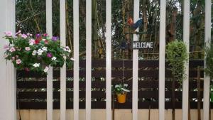 une clôture blanche avec des fleurs et un panneau de bienvenue dans l'établissement The Nine Mansion, à Ubon Ratchathani