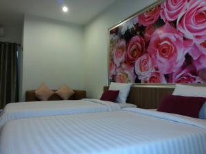 two beds in a room with a painting on the wall at The Nine Mansion in Ubon Ratchathani