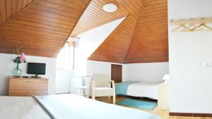 a bedroom with two beds and a wooden ceiling at Hospedaria Pielas in Sintra