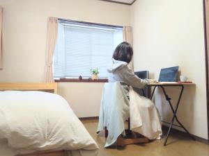 a woman sitting at a desk with a laptop at 民泊よこてこよ in Yokote