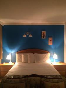 a bedroom with a blue wall and a bed with two lamps at Marine Inn in Powell River