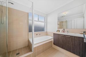 a bathroom with a tub and a sink and a shower at Garrison Cottage in The Vines +26 photos