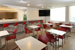 a restaurant with white tables and red chairs at City Express Junior by Marriott Cancun in Cancún