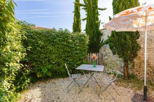 a table and chairs with an umbrella in a garden at Gite Les Jardins d'Harmonie in Bourgneuf
