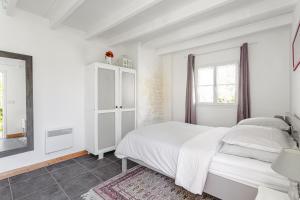a white bedroom with a bed and a mirror at Gite Les Jardins d'Harmonie in Bourgneuf