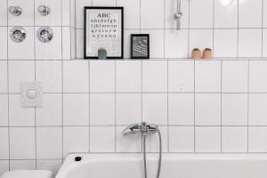 a white tiled bathroom with a sink and a tub at City Retreat Zwickau mit Balkon zum Innenhof in Zwickau +11 photos