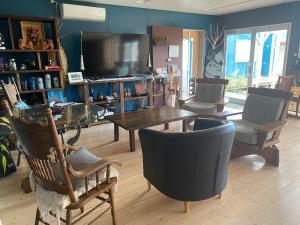 a living room with a table and chairs and a tv at 民宿あわい in Nakijin