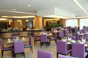 a dining room with purple chairs and tables at Angkasa Garden Hotel in Pekanbaru