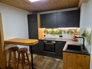 a kitchen with black cabinets and a table and stools at Petererhof in Ellmau