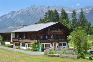 a large wooden house with mountains in the background at Petererhof in Ellmau