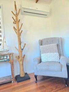 a living room with a blue chair and a fake tree at Beach House in Surf Beach