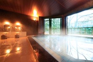 a swimming pool in a room with a large window at Yutorelo Karuizawa Hotel in Karuizawa