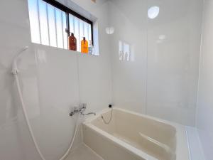 a white bathroom with a bath tub and a window at 晴の川 in Wakayama