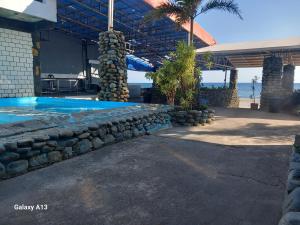 a house with a swimming pool and a stone wall at White Castle Beach Resort in Iba