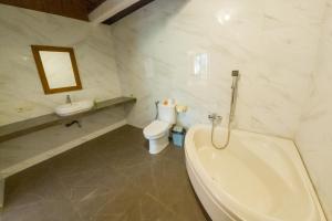 a bathroom with a tub and a toilet and a sink at Capung Cottages in Ubud
