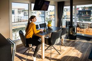 a woman sitting at a table with a laptop at Floatinghouse Grasshopper in Klitten +25 photos