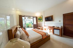 a bedroom with a bed and a television and a tub at Capung Cottages in Ubud