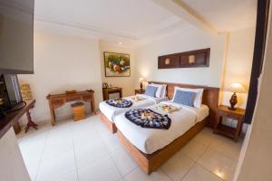 a hotel room with two beds and a television at Capung Cottages in Ubud