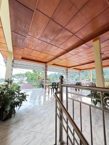 a balcony with a wooden ceiling and tables and chairs at Toba Boi in Tuktuk Siadong